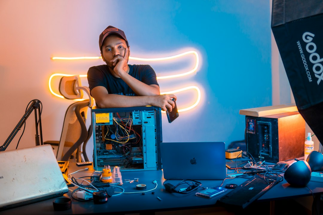 heros-img A tech enthusiast leans on an open CPU, surrounded by gadgets and tools on a vibrant, neon-lit workspace, reflecting a creative and tech-savvy vibe.