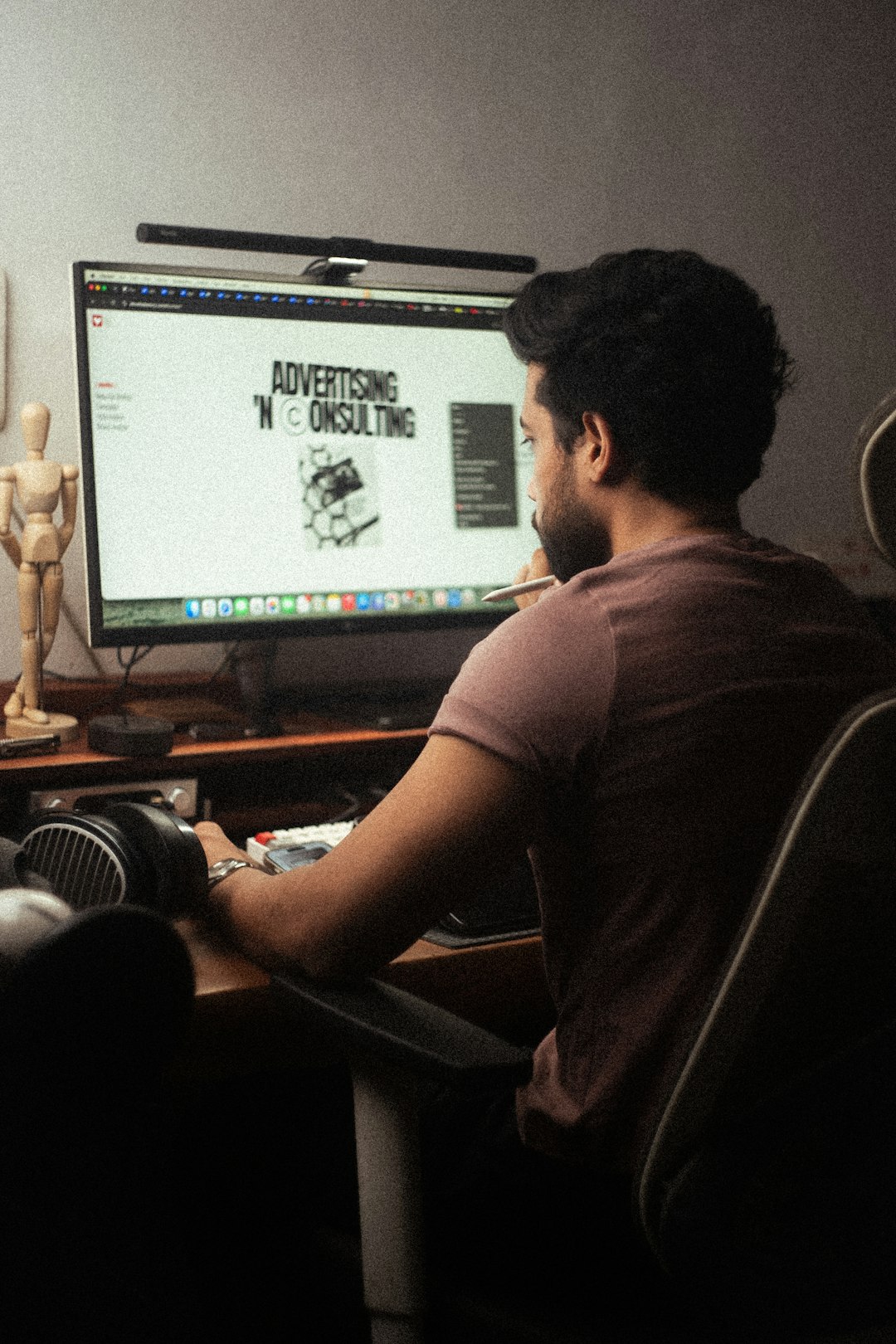 A focused designer deeply immersed in work, using a digital tablet while listening to music on headphones. The workspace blends natural light, an industrial aesthetic, and creative energy, making it an inspiring setup for productivity and artistic exploration.